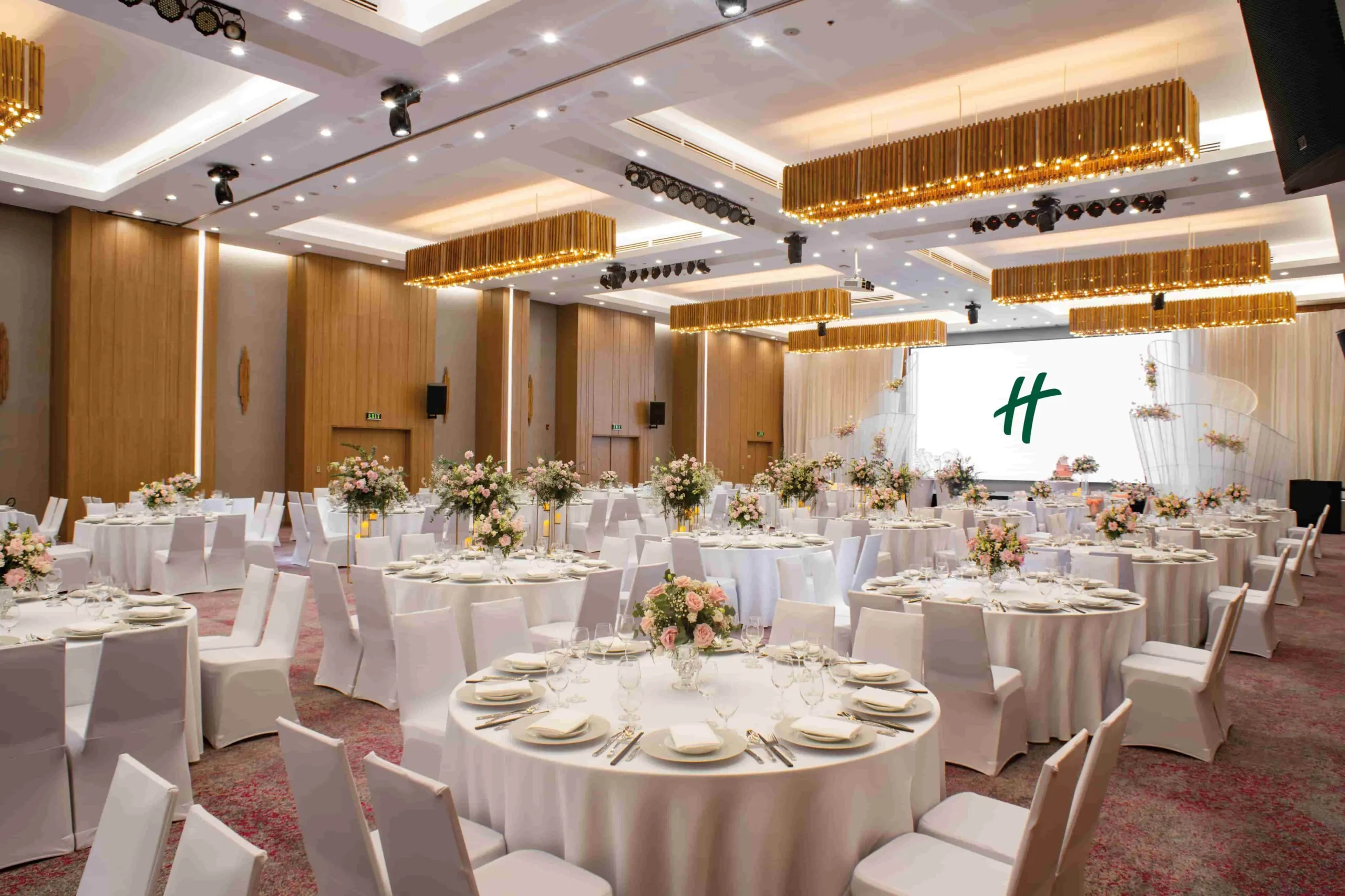 Không gian tiệc cưới Grand Ballroom tại Holiday Inn & Suites Saigon Airport với setup bàn tiệc sang trọng và ánh sáng ấm